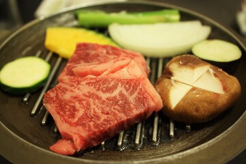 Sliced raw beef meat and variety of vegetable on the black grill plate for Yakiniku, isolated on black background. Top view - 焼肉 野菜