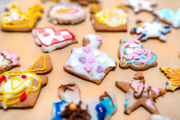 Hand decorated baked gingerbreads of various shapes, arranged on baking paper.