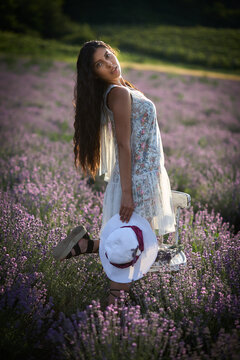 Portrait of lovely brunette girl with hat on lavender field background.