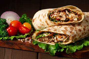 Shawarma, roll in lavash , grilled meat, with vegetables, sandwich , on a wooden brown background,...