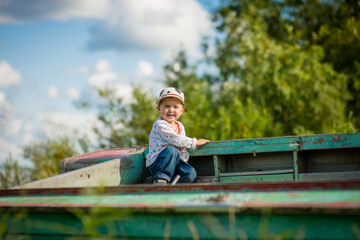 Fototapeta premium child playing in a boat on the riverbank, selective focus