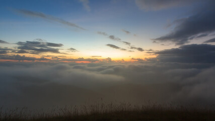 Abstract blurry shot of sunrise or sunset over foggy clouds in the mountain forest for backdrop or background.