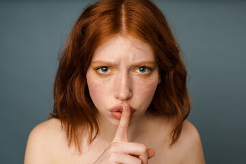 Naklejka premium Shirtless displeased woman with makeup showing silence gesture at camera
