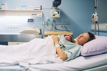Mother and newborn. Child birth in maternity hospital. Young mom hugging her newborn baby after delivery. Woman giving birth.