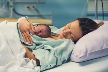 Obraz na płótnie Canvas Mother and newborn. Child birth in maternity hospital. Young mom hugging her newborn baby after delivery. Woman giving birth.