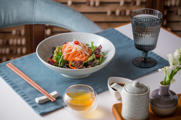 Fresh green salad with smoked salmon and mixed leaves on the table at restaurant