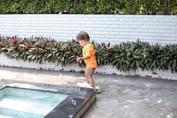 little toddler girl walks in adult shoes by the swimming pool