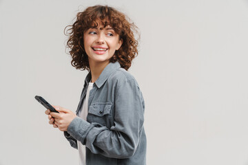 Fototapeta premium Young ginger joyful woman smiling while using mobile phone