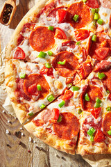 Pepperoni pizza with pizza sauce, mozzarella cheese and pepperoni. Pizza on wooden board on wood table with ingredients.