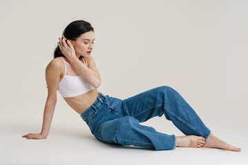 Young brunette woman with vitiligo sitting on floor