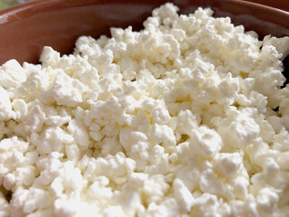 Curd cheese in clay bowl, closeup view, cottage cheese closeup