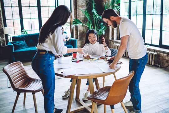 Cheerful colleagues brainstorming on project in creative workspace