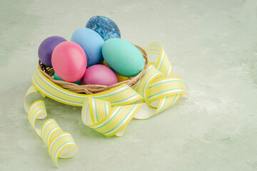 colorful easter eggs with yellow ribbon on green with copy space