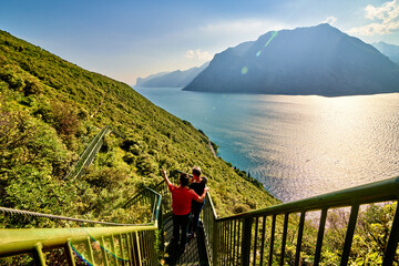 Fototapeta na wymiar Panoramic view on Lake Garda from the Busatte-Tempesta trail near Nago-Torbole with the iron staircase, Torbole town surrounded by mountains in the summer time,Italy