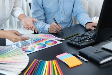 graphic designer team working on web design using color swatches editing artwork using tablet and a...