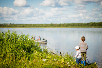 Fototapeta na wymiar boys look at a boat on the riverbank, selective focus