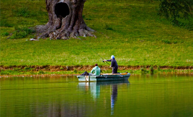 two people on a fishing boat fishing on a calm lake in Blenheim Palace ,Oxford