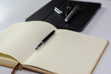 Notebook and fountain pen on white background.