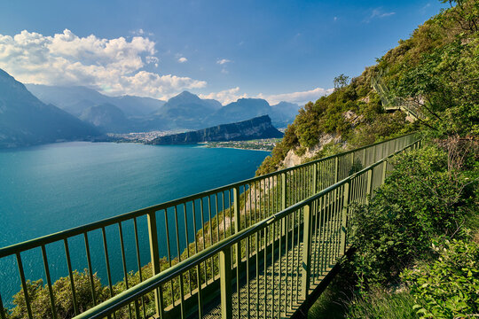 Panoramic view on Lake Garda from the Busatte-Tempesta trail near Nago-Torbole with the iron staircase,  Torbole  town surrounded by mountains in the summer time,Italy