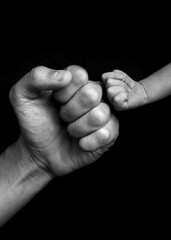 hands fists father and son on black background, black and white 