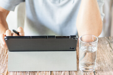 A man uses tablet to communicate internet on brown wooden table with blur background.