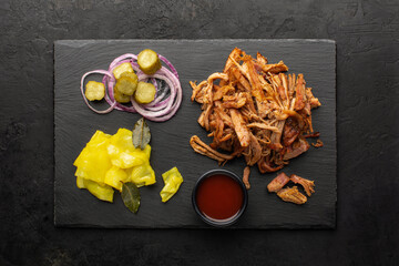 Smoked pulled pork and pickled vegetables set on a slate board, top view. american texas barbecue.