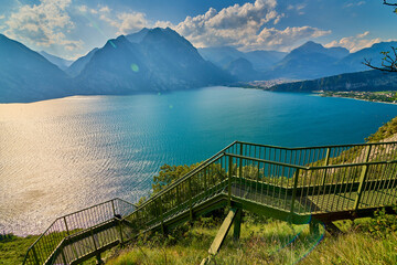 Panoramic view on Lake Garda from the Busatte-Tempesta trail near Nago-Torbole with the iron staircase,  Torbole  town surrounded by mountains in the summer time,Italy
