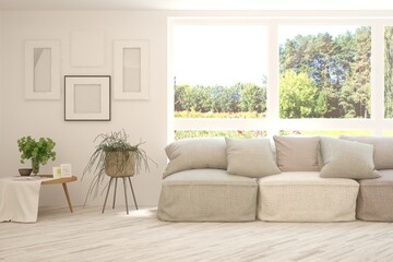 Fototapeta premium White living room with sofa and summer landscape in window. Scandinavian interior design. 3D illustration