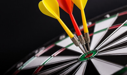 Red and yellow darts arrows on center of dartboard. Concept o business target, success and win.