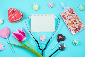Pink tulips and stethoscope with spiral notepad with Happy Doctors Day text on it.