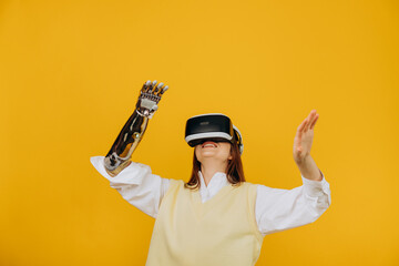 Smiling young person in white shirt with metal bionic arm and virtual reality headset plays game on...