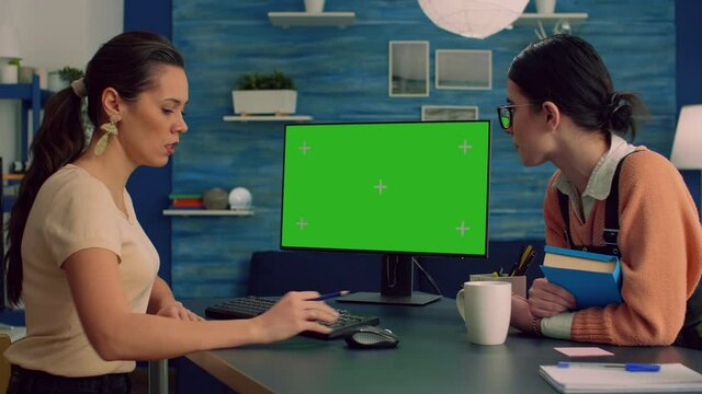 Teammates browsing on internet for commerce advertising using powerful computer with mock up green screen chroma key display. Collegues working on isolated pc sittings at desk table in office studio