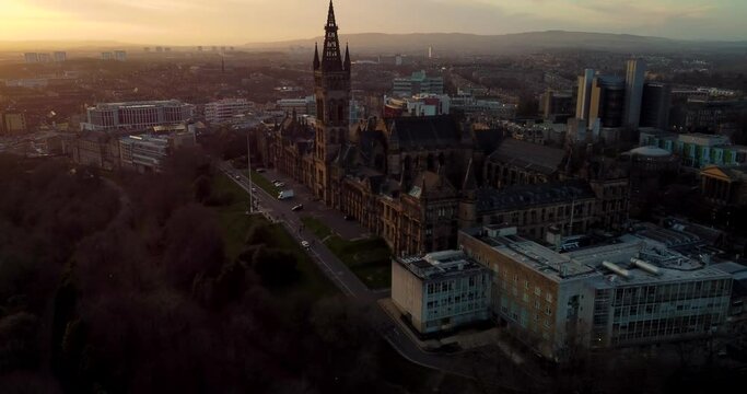 Flying in spring at sunset over the Kelvingrove park in Glasgow, Scotland towards the Gilbert Scott tower at Glasgow University.