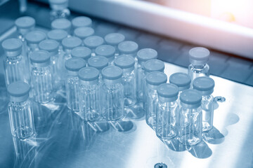 The pile of glass bottles for vaccine container. The medical equipment in light blue scene.