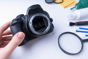 Master's hand holds dslr camera, camera cleaning accessories on white background