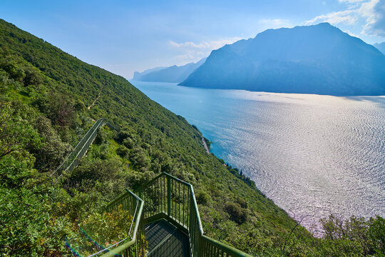 Panoramic view on Lake Garda from the Busatte-Tempesta trail near Nago-Torbole with the iron staircase,  Torbole  town surrounded by mountains in the summer time,Italy