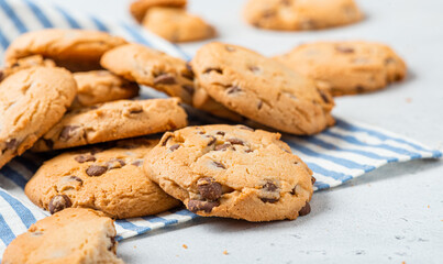 Heap of chocolate chip cookies on a gray table close-up. Sweet breakfast. Stack of traditional chip cookies with chocolate chunks.
