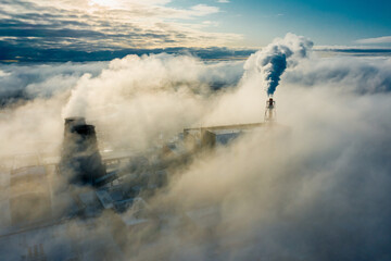 Obraz premium large clouds of white smoke cover power plant territory under bright sunlight on frosty winter day aerial view