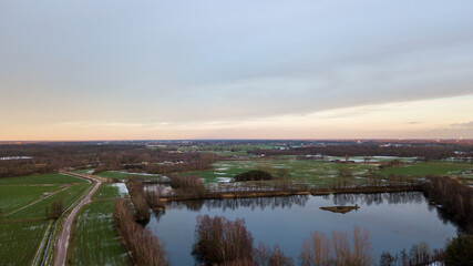 Aerial view of a beautiful and dramatic sunset over a forest lake reflected in the water, landscape drone shot. Blakheide, Beerse, Belgium. High quality photo