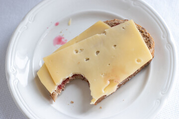 A bite of a Slice of bread with cheese on white plate
