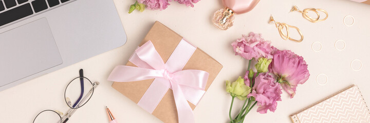 Banner with scattered laptop, gifts, flowers and feminine accessories on a beige background. Online celebrate or shopping concept.