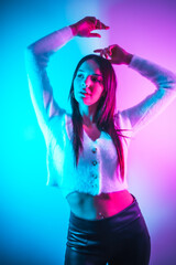 Party lifestyle in a nightclub with pink blue neon lights, portrait of a young brunette Caucasian woman in a white wool sweater