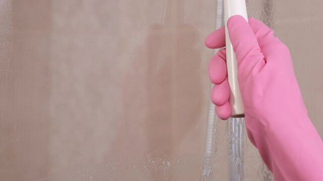 Woman In Pink Rubber Gloves Cleans Glass Door In Shower Cabin With Squeegee And Detergent For Windows. Housewife, Housekeeper Is Washing Bathroom. Working In Home, Hotel Cleaning .