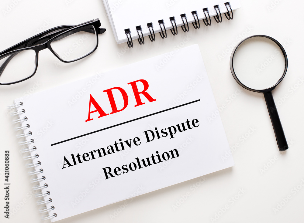 Poster adr alternative dispute resolution is written in a white notebook on a light background near the not