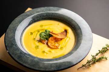 Cream pumpkin soup with grilled shrimp. Soup in a blue plate on a black background.