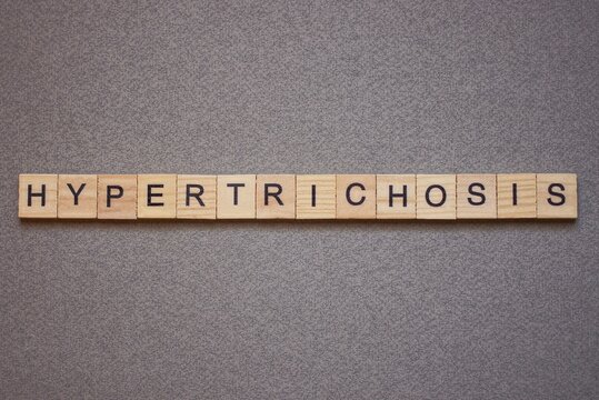 text the word hypertrichosis from brown wooden small letters with black font on an gray table