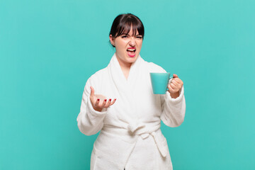 young woman wearing bathrobe looking angry, annoyed and frustrated screaming wtf or what’s wrong...