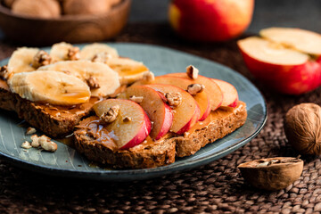 Toasts with peanut butter, apple, banana, walnut and honey. Healthy vegetarian breakfast concept.