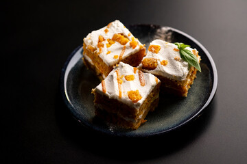 Carrot dessert cake on a plate on a black background.