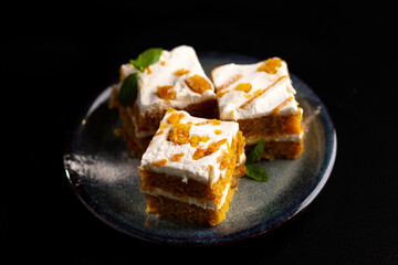 Carrot dessert cake on a plate on a black background.